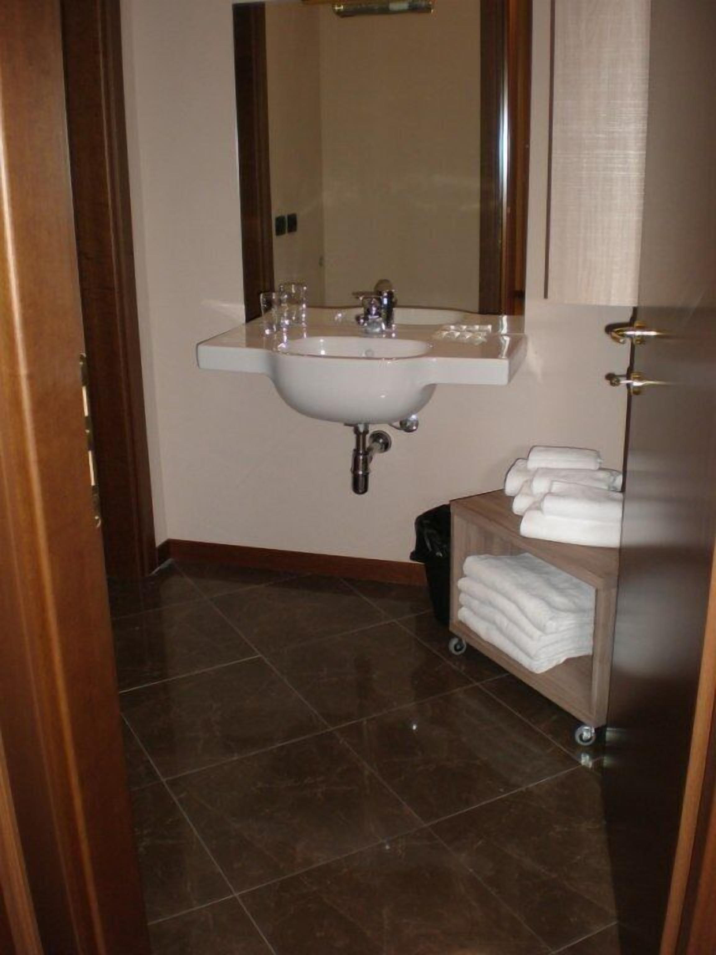 Un bagno con lavandino, specchio e porta asciugamani.