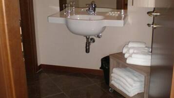Un bagno con lavandino, specchio e porta asciugamani.