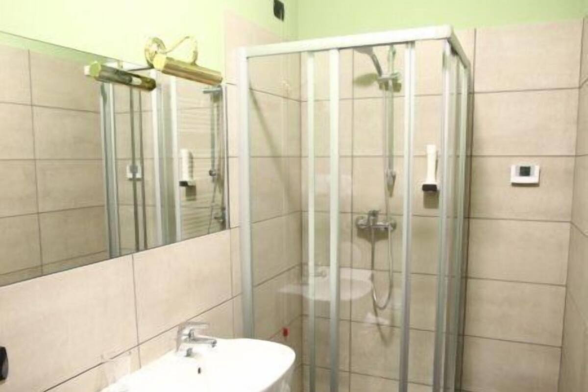 Une salle de bain moderne avec une douche à parois de verre, un lavabo blanc et un miroir.