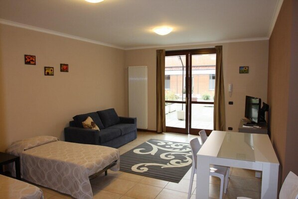 A room with a bed, a sofa, a dining table, and a TV. - Valtidone Hotel (Borgonovo Val Tidone)