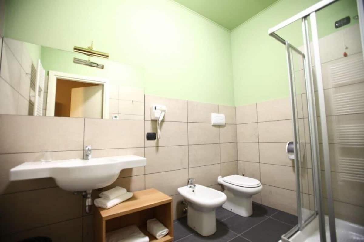 Une salle de bain équipée d’un lavabo, de toilettes, d’un bidet et d’une douche à parois en verre.