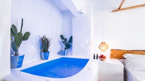 Un bagno moderno con una vasca, piante in vaso, una testiera in legno e un comodino con una ciotola di frutta.