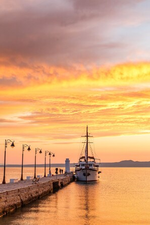 A waterfront scene with a dock, a boat, and a row of street lamps. - Hotel Marabou (Kassandra)