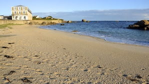 A beach with a building on the left.