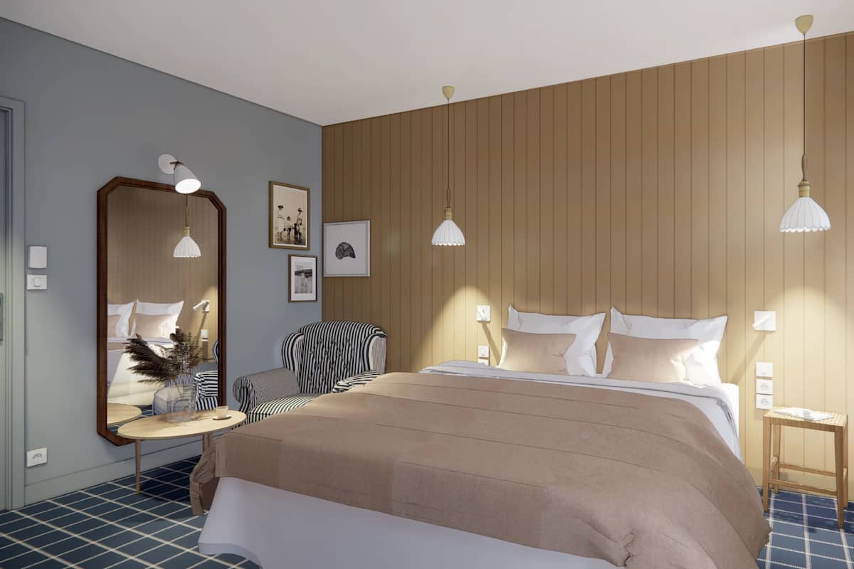 A modern bedroom with a large bed, a bedside table, a chair, a mirror, and wall-mounted lights.