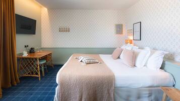 A hotel room with a bed, bedside table, and a desk with a chair.