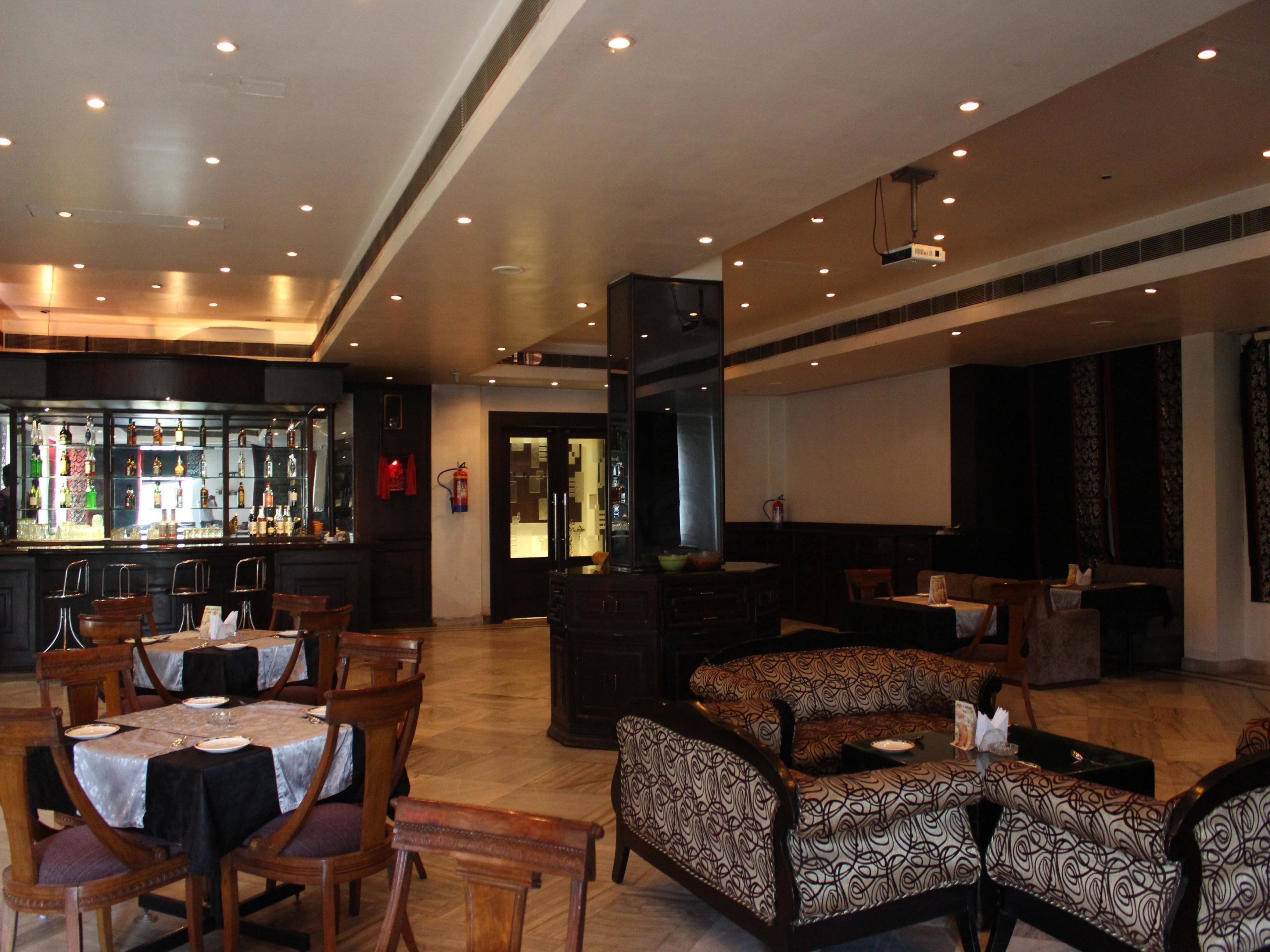 A spacious lobby with a bar area, seating arrangements, and a stage for presentations.
