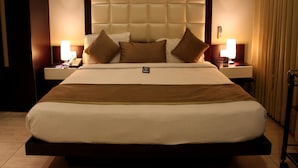Una cama grande con cabecera acolchada, dos mesitas de noche con lámparas y un panel de control en la cama.