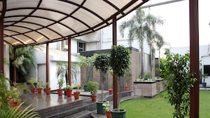 Un espacio al aire libre cubierto con plantas en macetas, piso de baldosas y césped.