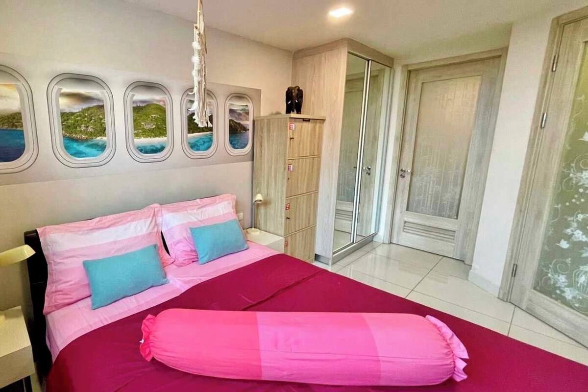 A bedroom with a bed, a wardrobe, a nightstand, and a view through the window.
