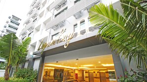 A hotel entrance with a glass facade, palm trees, and a modern interior design. - Laguna Bay 2 by PSR ASIA (Pattaya)