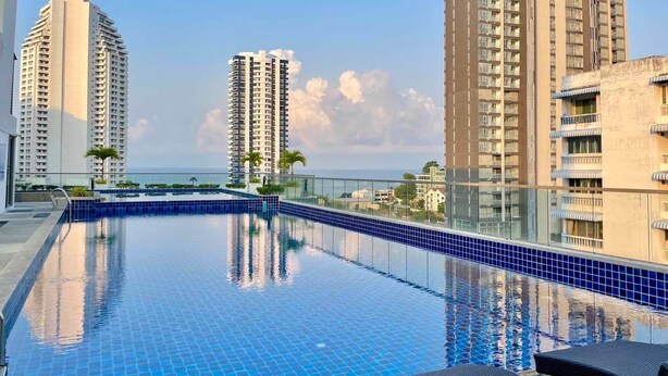 A rooftop swimming pool with clear blue tiles, surrounded by high-rise buildings and a view of the sea. - Laguna Bay 2 by PSR ASIA (Pattaya)