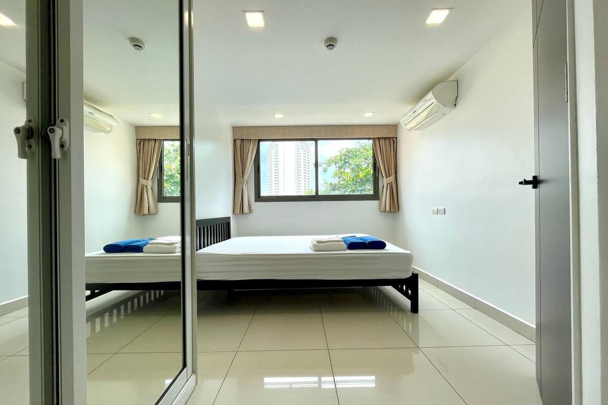 A hotel room with a bed, a window, and a view of a building outside.