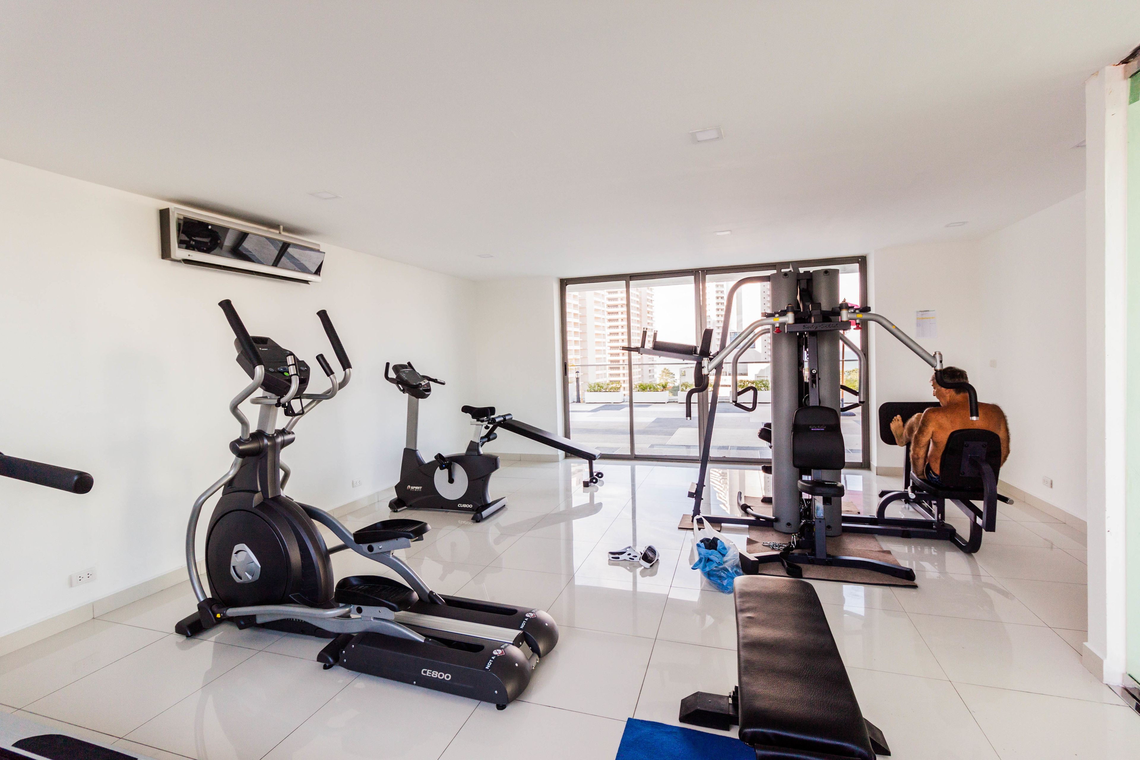 Une salle de sport équipée de machines de cardio, de matériel de musculation et d’un banc.