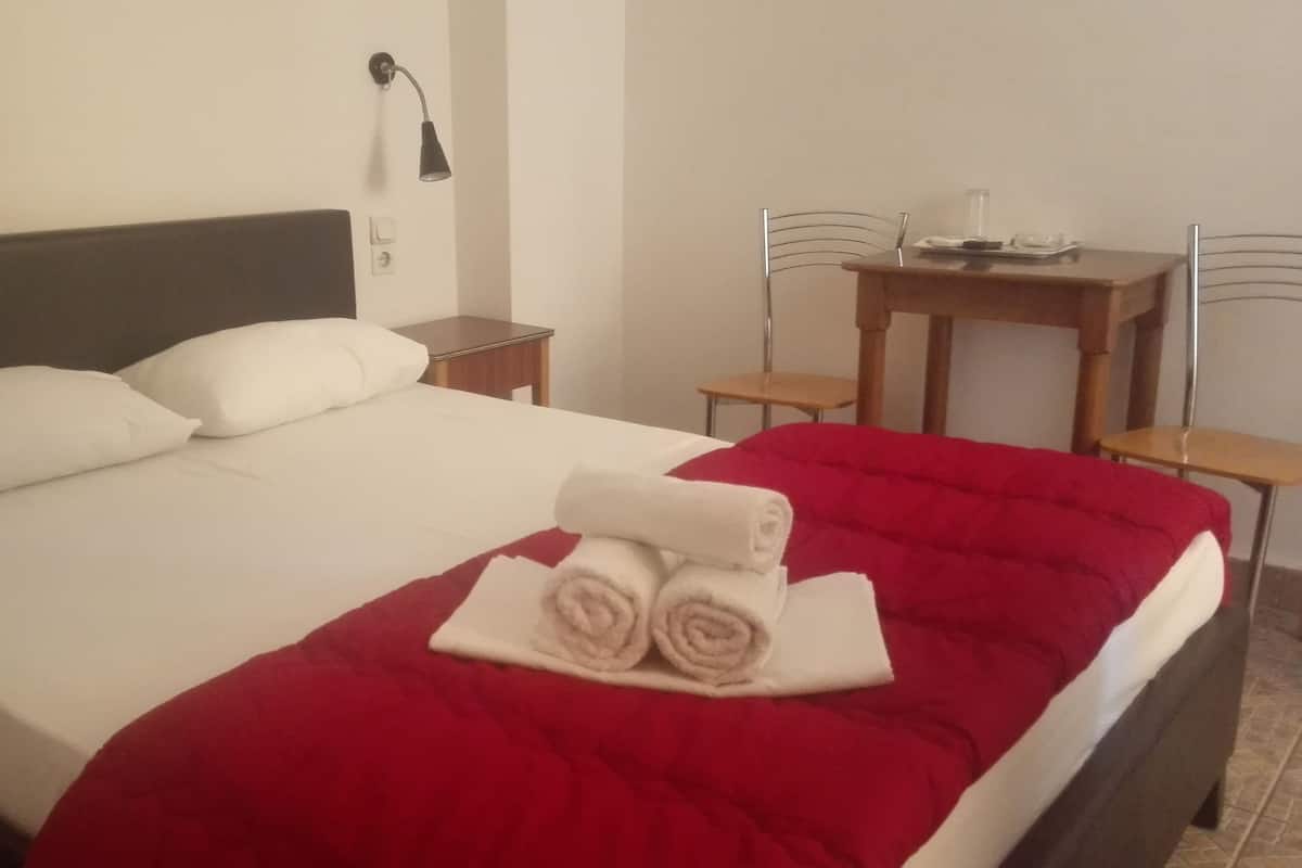 Una habitación de hotel con cama, escritorio, silla y lámpara.