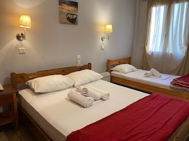 Habitación de hotel con dos camas, cabecero de madera, lámpara de pared y ventana con cortinas.