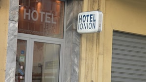 Et hotel kaldet "HOTEL IONION" med en facade af marmor og en lukket stormskodde.