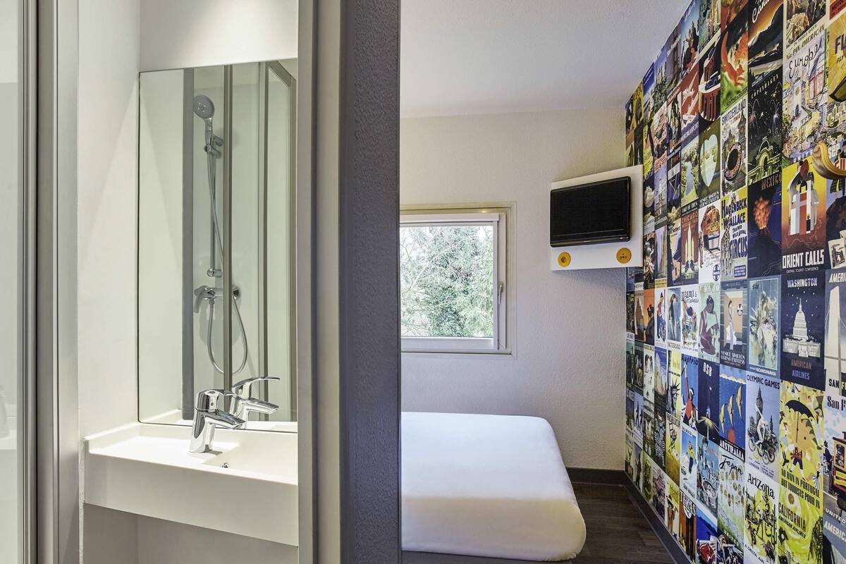 A bathroom with a shower, sink, and a wall decorated with travel posters.