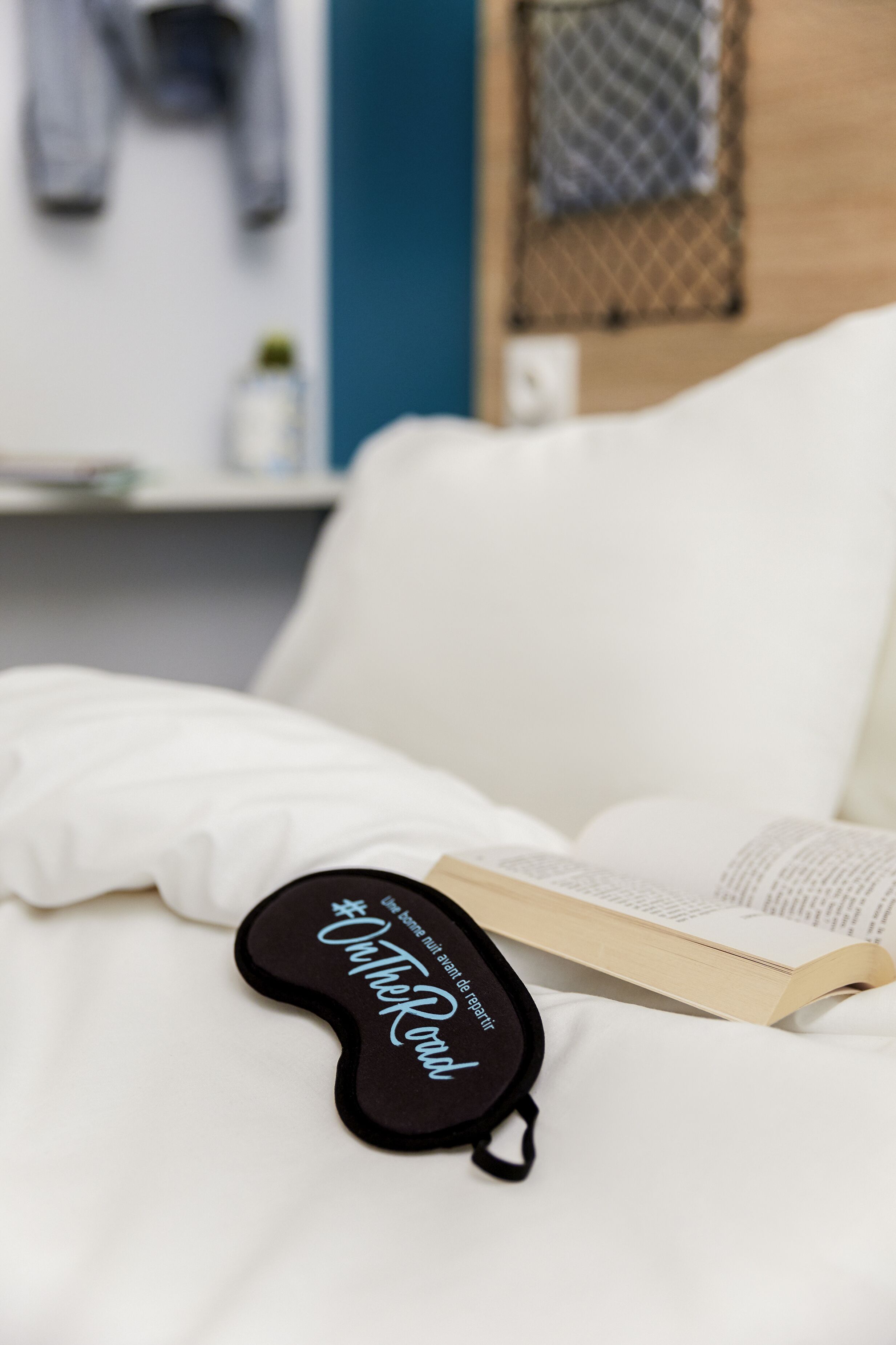 Ein Bett mit einem schwarzen Kopfkissen und einem offenen Buch.