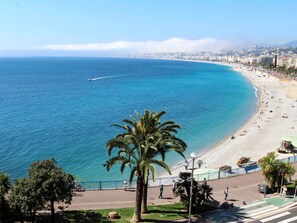 Eine Küstenstadt mit Strand, Palmen und tiefblauem Meer.