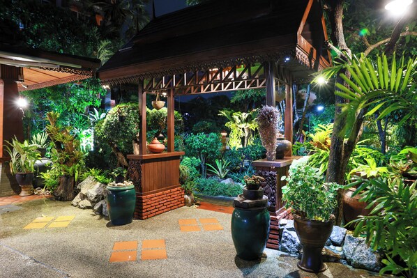 A covered outdoor area with a wooden structure, potted plants, and a stone pathway. - Baan Vanida Garden Resort (Karon)