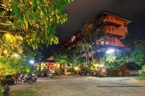A multi-story building with a well-lit entrance and parked motorcycles in front. - Baan Vanida Garden Resort (Karon)