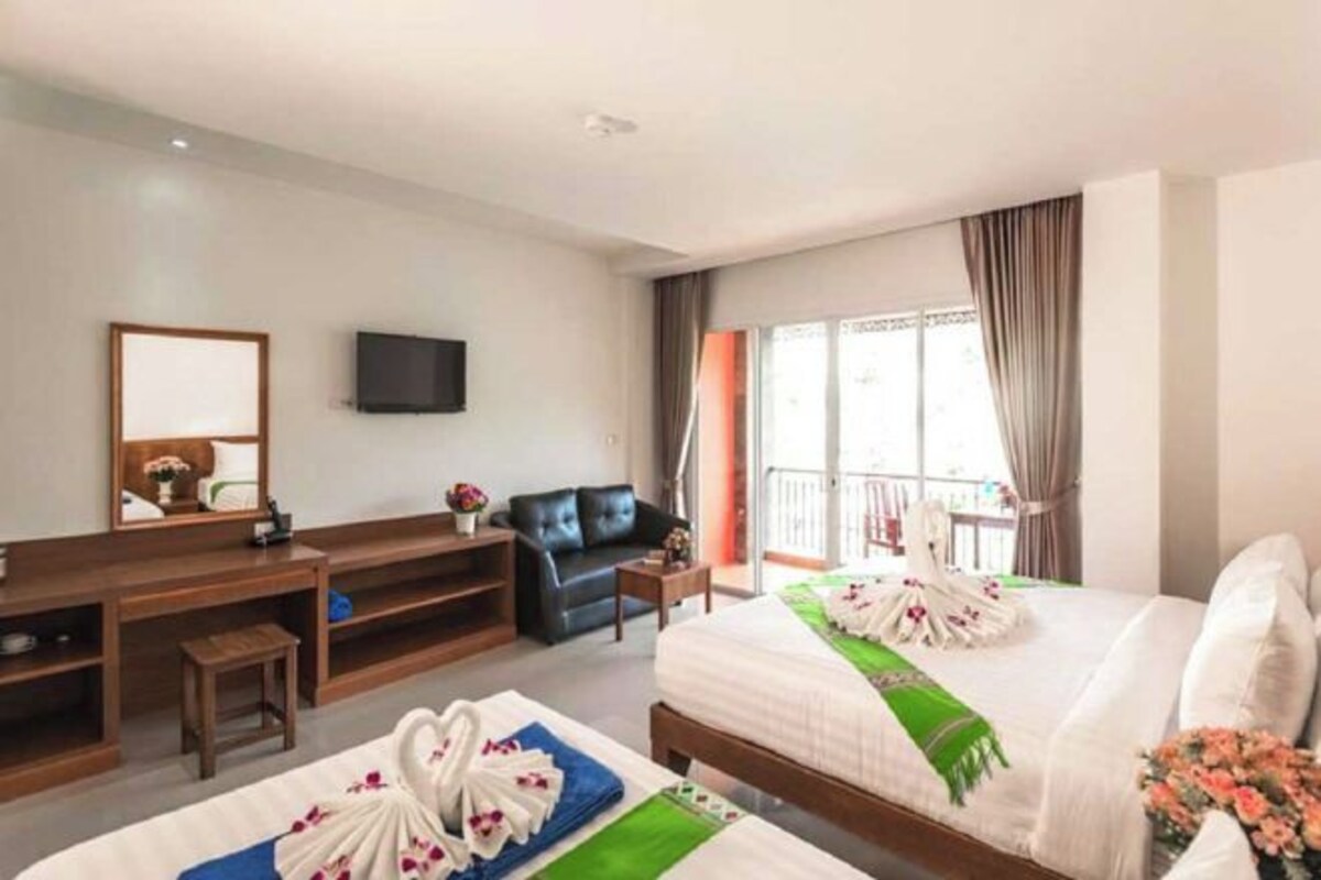 A hotel room with a bed, a desk, a television, and a balcony.