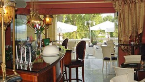 Un restaurant doté d’un bar, de chaises blanches et de parasols à l’extérieur.