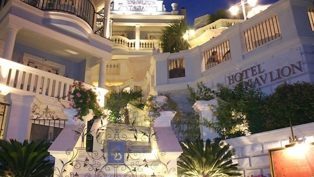 Un hôtel à plusieurs étages doté de balcons, d’une enseigne indiquant « HÔTEL HAVLON » et d’éléments décoratifs en fer forgé.