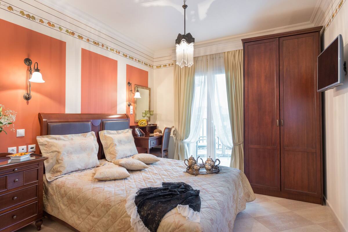 Une chambre avec un grand lit, une armoire en bois et un téléviseur fixé au mur.