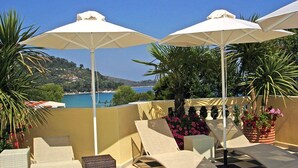 Une terrasse dotée de chaises longues et de parasols, offrant une vue sur la côte.