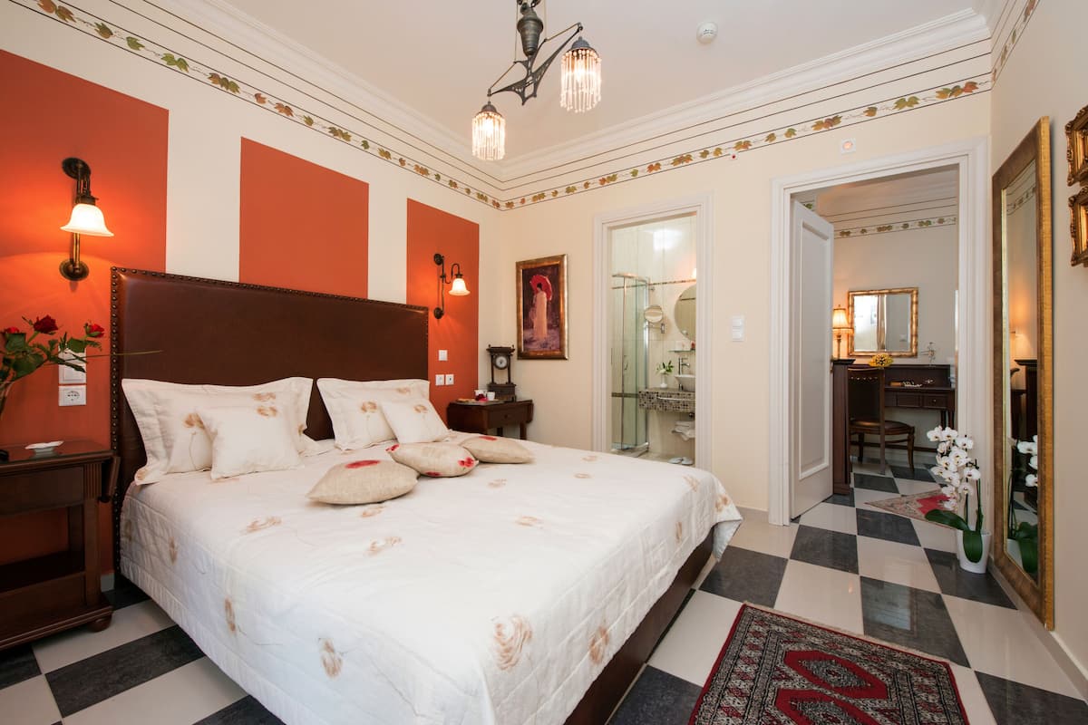 Une chambre d’hôtel avec un grand lit, un bureau et une salle de bain visible à travers une porte ouverte.