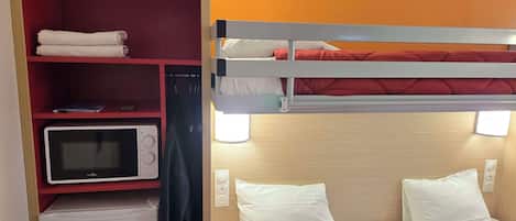 A compact hotel room with a bunk bed, a microwave, a small refrigerator, and a red shelf with towels.