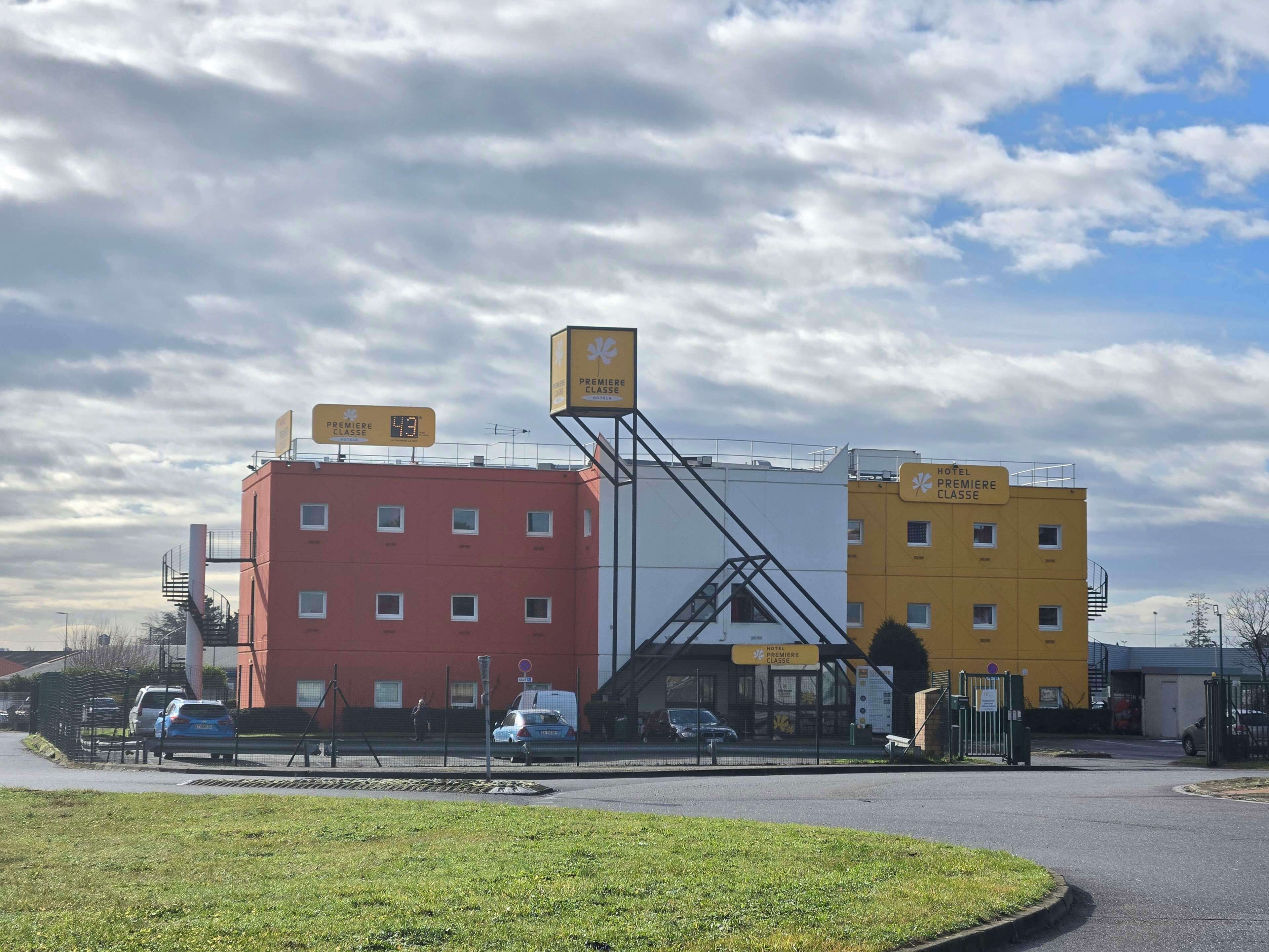 A hotel with a red and yellow building, a staircase, and a sign indicating the hotel is for the premiere class.
