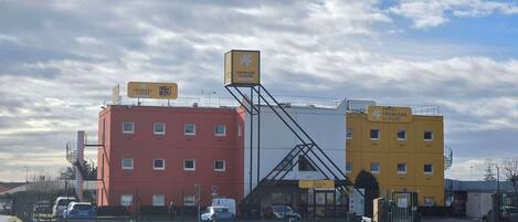 A hotel with a red and yellow building, a staircase, and a sign indicating the hotel is for the premiere class.