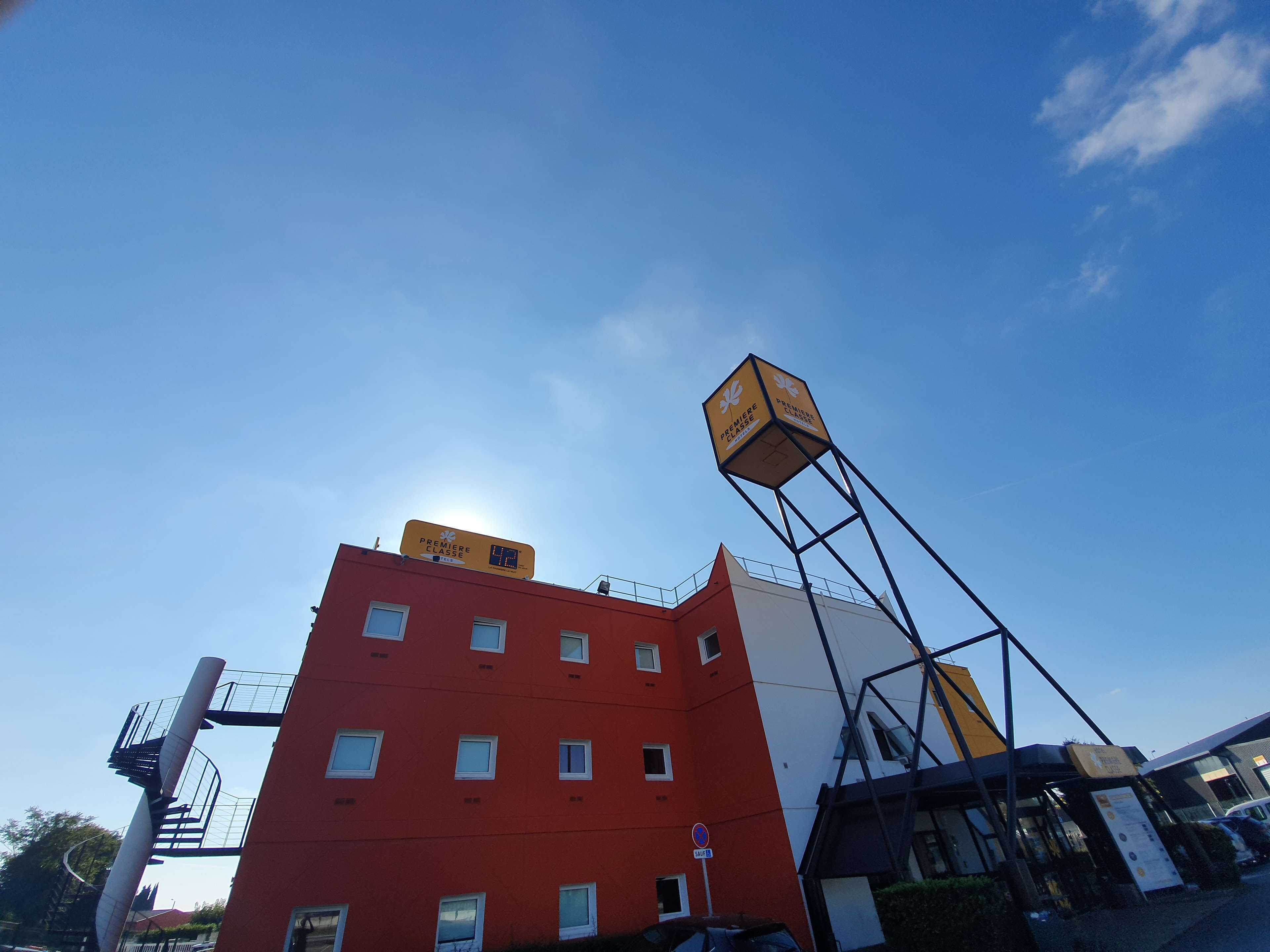 Un immeuble à plusieurs étages doté d’une façade rouge, d’une enseigne jaune bien visible et d’un escalier en colimaçon au design original.