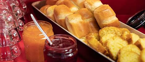 A tray of breakfast items including rolls, biscuits, and jams.