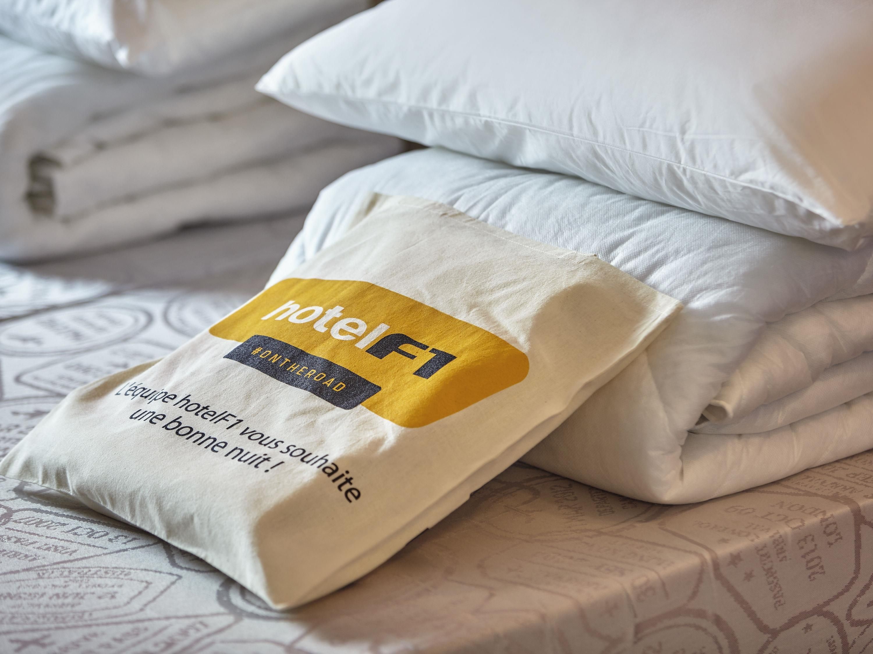 Una cama bien hecha con almohadas y una manta doblada.