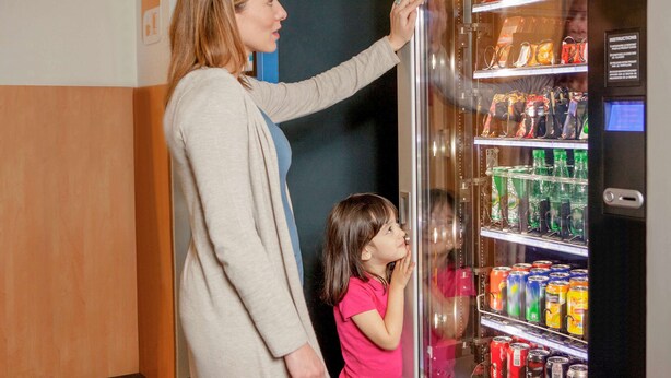 A woman and a child standing in front of a vending machine with various snacks and drinks. - hotelF1 Lyon Gerland Vénissieux (Venissieux)