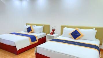 Habitación de hotel con dos camas, cada una con cabecera, ropa de cama blanca y correpasillos a rayas azules y amarillas.