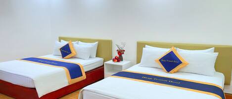 A hotel room with two beds, each with a headboard, white bedding, and blue and yellow striped bed runners.