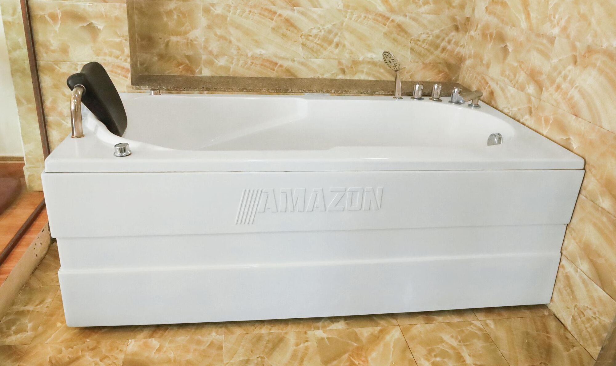 A white Amazon-branded bathtub in a bathroom with marble tiles.