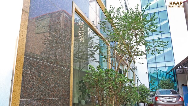 Een modern gebouw met een glazen gevel, een geparkeerde auto en plantenbakken op de voorgrond.