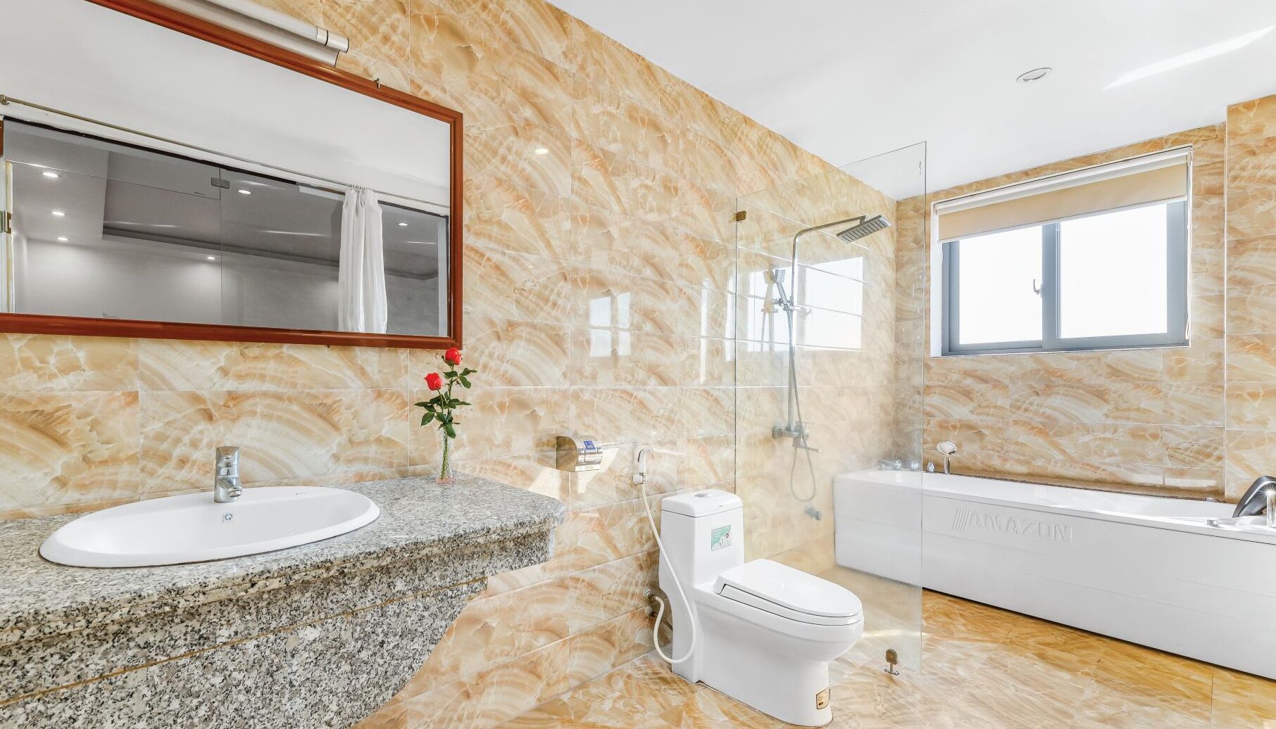 A modern bathroom with a marble wall, a sink, toilet, and a bathtub.