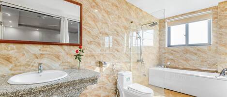 A modern bathroom with a marble wall, a sink, toilet, and a bathtub.