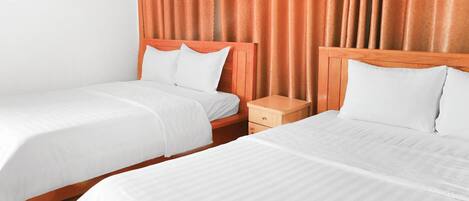 Two single beds with wooden headboards, white bedding, and a nightstand with a drawer.