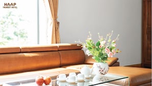 Een moderne woonkamer met een glazen salontafel, een bloemenvaas en een set witte theepotten en kopjes.