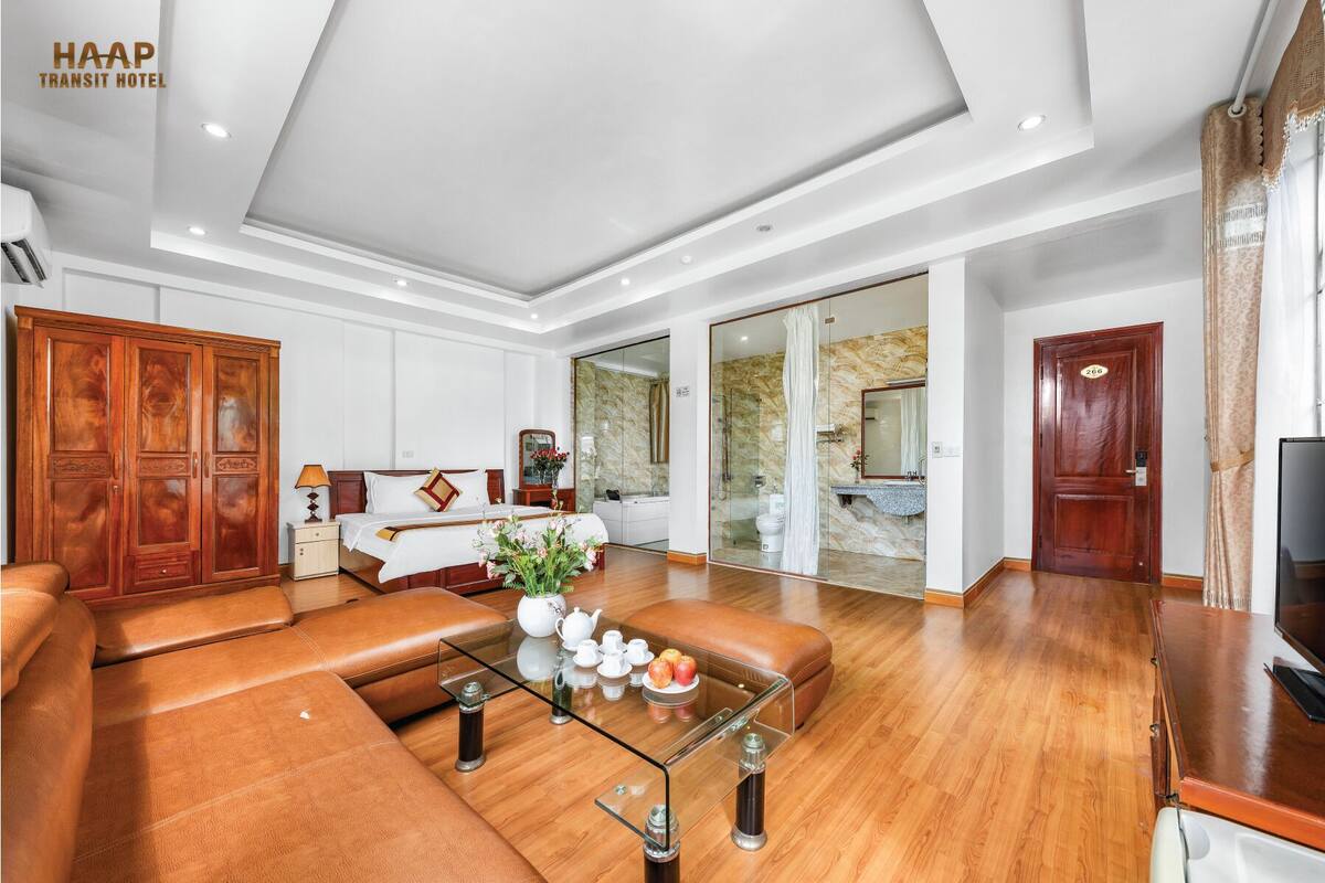 A spacious living room with a sofa, a glass coffee table, and a wooden cabinet.