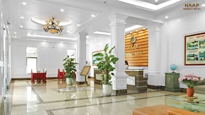 Een hotellobby met een receptiebalie, een zithoek en een grote kroonluchter.