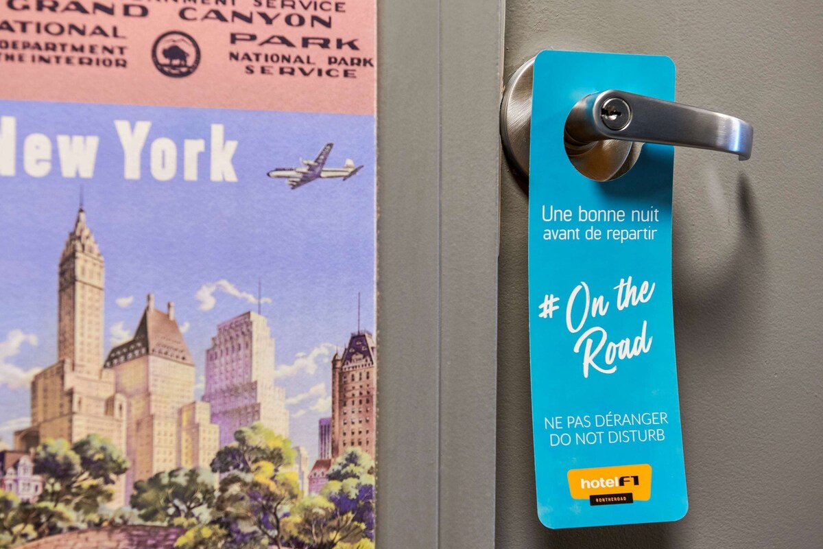 A hotel room door with a blue tag that reads "On the Road" and "NE PAS DÉRANGER DO NOT DISTURB" in French.